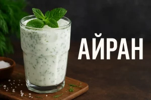 Стакан айрана с зеленью и надписью АЙРАН на фоне